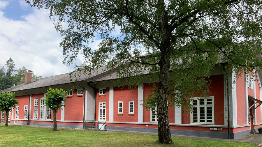 Gutshof mit roter Fassade und weiß abgesetzten Fassadenteilen und Fenstern