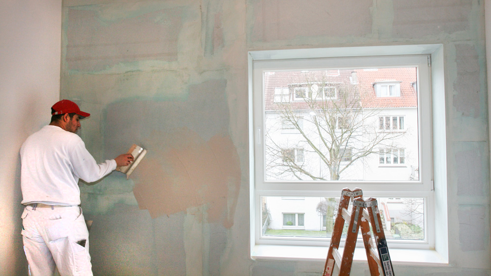 Maler verputzt eine Innenwand